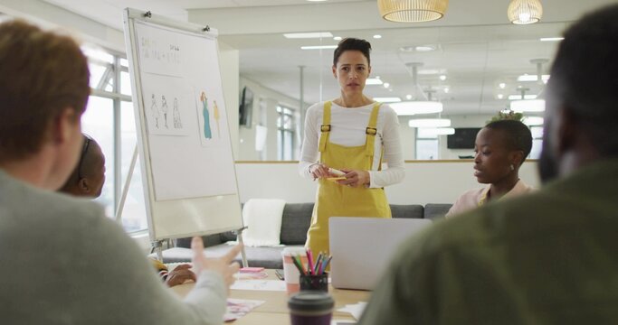 Presenting presenter in yellow overalls and white top leading meeting at office, with flip chart