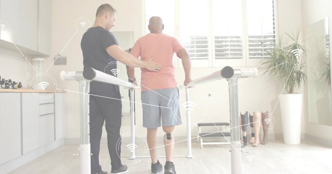 Walking man in pink tee on parallel bars in rehab room, therapist guiding, sensor and prosthetics