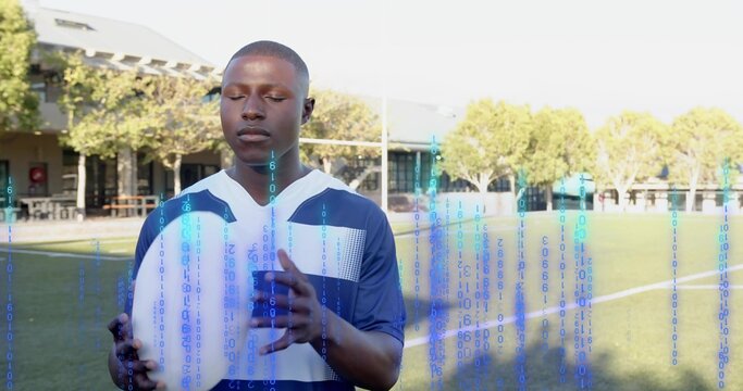 Holding white rugby ball, man in blue-and-white jersey closing eyes on campus field, binary overlay