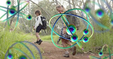 Hiking two women walking narrow trail in woods wearing jackets backpacks hiking boots neon graphics