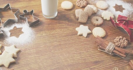 Arranging baked cookies and metal cutters on home kitchen table with powdered sugar star and milk