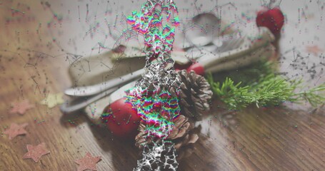 Showing pine cones, red bauble, green sprig and silver cutlery on napkin at wood table, glitch