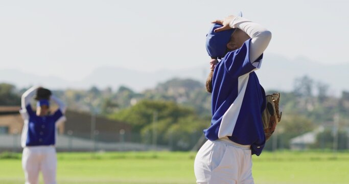 Holding glove, female player in blue jersey placing hands on head in outfield, with blue caps - Powered by Adobe