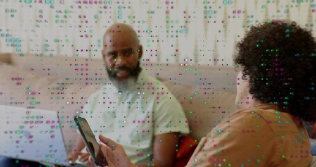 Sitting two men showing smartphone, laptop on sofa, at home, light and rust shirts, glitch overlay