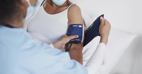 Taking senior patient blood pressure on exam bed, nurse in scrubs adjusting blue INDEX cuff