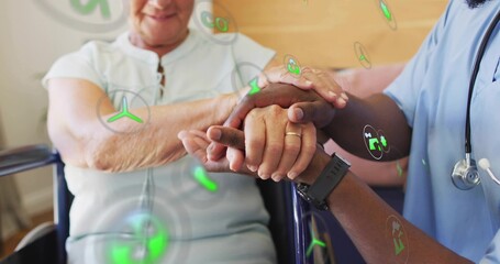 Placing caregiver hand on senior's hand in clinic, showing blue scrubs, AR icons, gold ring, watch