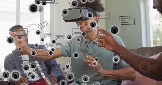 Reaching man wearing VR headset, green polo, using AR interface on sofa at home, chat bubbles