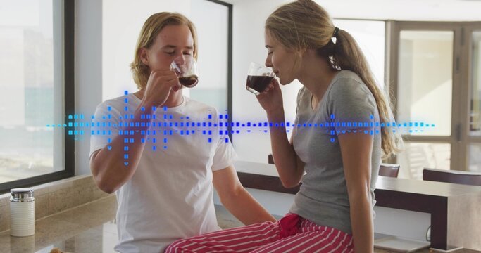Sipping couple holding clear mugs in home kitchen, woman in striped PJs, with waveform overlay