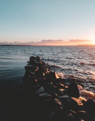 Serene Seascape with Rocky Jetty at Sunset Over Calm Waters