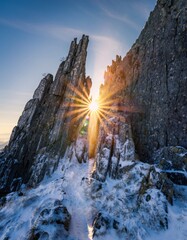 Dramatic Mountain Landscape with Snow and Sunlight Burst at Dusk