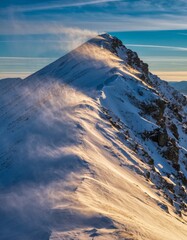 Majestic Snow-Capped Mountain Peak with High Winds and Sunlight