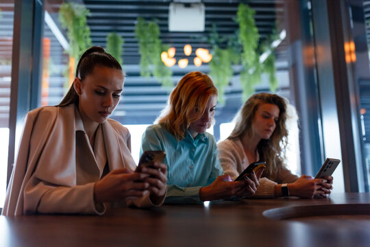 Businesswomen engaged in mobile communication at a stylish cafe during a networking event in an urban setting