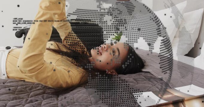 Woman lying bed holding device overhead reading and laughing as tech dotted globe overlaying face