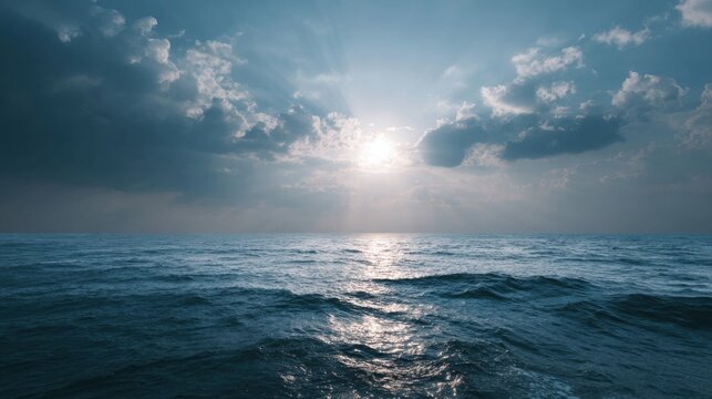 Deep blue ocean waves under a cloudy sky with bright sun rays breaking through
