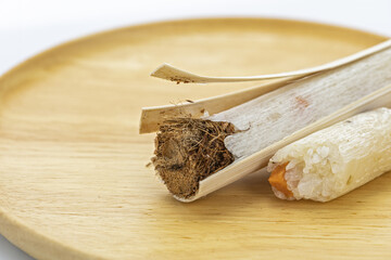 Close-up of Thai traditional glutinous rice with savory yam wrapped inside a bamboo stick, partially peeled open to reveal