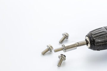 Close-up of a black grip release screwdriver with hex socket bit and four silver metal screws on white background