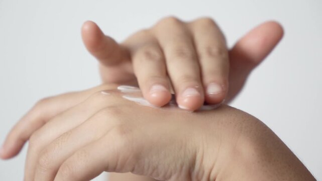 Close-up of hands applying and rubbing cream lotion into the skin