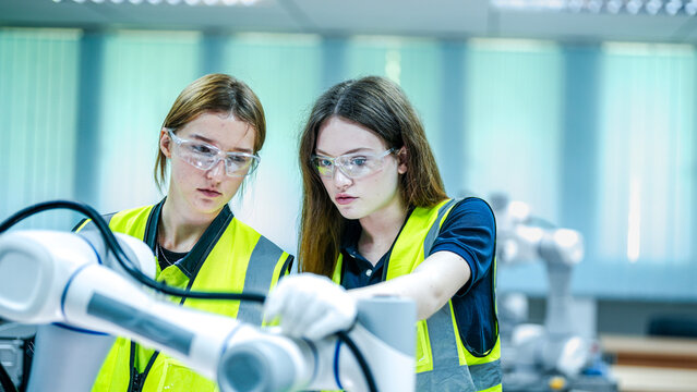 Two smiling female engineers represent the future of work. They are using artificial intelligence and robotics to optimize the high tech manufacturing supply chain.