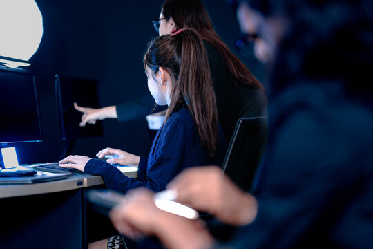 Focused female professionals collaborating late night in modern tech hub. Team members analyze data review designs pointing at screen typing notes on tablet intense project grind.
