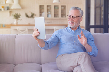 Cheerful grandfather mature senior caucasian man with grey hair having online video call zoom using digital tablet pad, talking with children, grandchildren ,calling his doctor. Active seniors life