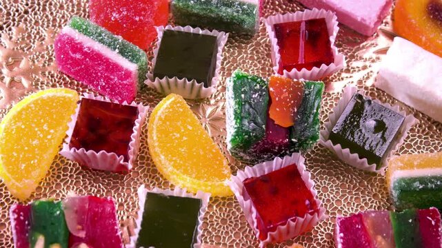 Spinning platter of traditional eastern sweets. Assortment of colorful Turkish Delight (Rahat Lokum) and sugar-coated citrus marmalade on a gold textured tray. Holiday dessert presentation.