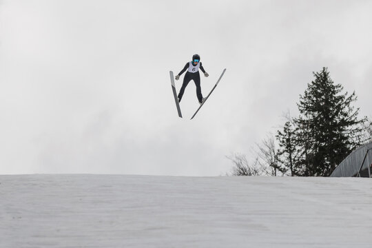 A ski jumper soars through the air at a snowy ski jumping site, showcasing skill and balance during the competition. - Powered by Adobe