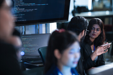 Monitoring AI training progress. Specialists oversee a machine learning model's training observing real time metrics on screen discussing adjustments via tablet interface late night.