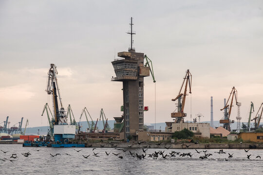 A scenic coastal view of an industrial Varna port featuring cranes and a watchtower