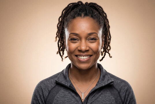 A confident close-up portrait of an Afro-American woman with styled dreadlocks.