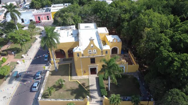 Aerial panning shot of the historic colonial church of La Ermita in M&eacute;rida, with the traditional park in the background, highlighting cultural and architectural heritage.