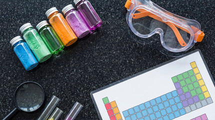 Flatlay of science supplies for World Science Day celebration featuring colorful powders and safety gear