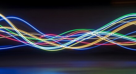 Abstract flowing neon light trails in blue yellow green and red against dark background glow energy