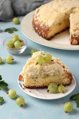 Homemade shortbread pie with green gooseberries and cut piece on plate on light blue background
