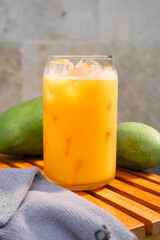 Portrait of a glass of mango juice placed on a wooden tray. Health drink concept