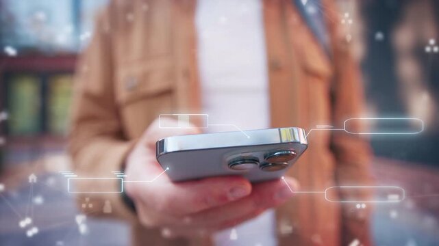 Male holding smartphone while reading message feed near modern building. Close view of hand interacting with device as digital interface elements floating around in soft outdoor environment.