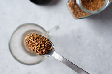 Top view a instant coffee in a spoon against the background of a glass jar with coffee.