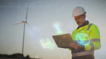 Caucasian engineer holding laptop and reviewing renewable energy visuals near wind turbine. Standing in open field at sunset while glowing hologram icons highlighting eco concepts surrounding device. - Powered by Adobe