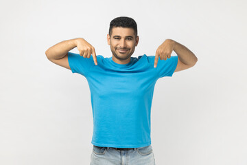 Smiling happy friendly man pointing down with both fingers, showing copy space for advertisement.