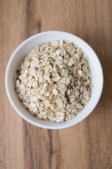Bowl of Dry Rolled Oats on Wooden Table