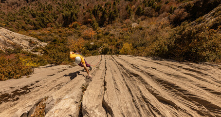 A man is climbing a rock face in a yellow shirt