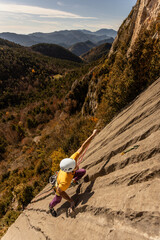 Obraz premium A man is climbing a rock wall with a yellow shirt and orange pants