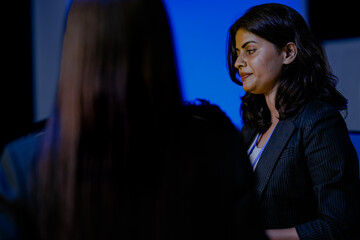 An Indian female software engineer or data scientist focuses during a technical briefing in a control room or at an AI developer conference. She is listening.