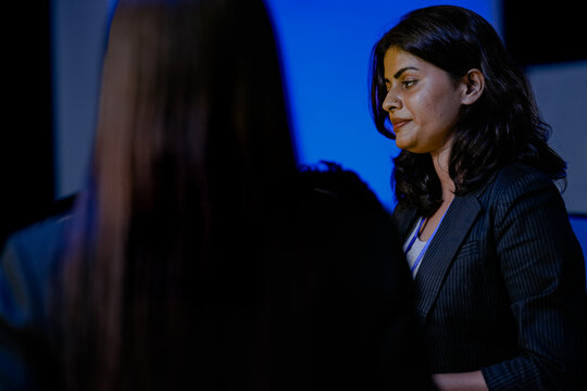 An Indian female software engineer or data scientist focuses during a technical briefing in a control room or at an AI developer conference. She is listening.