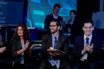 An Indian man with a tablet leads a discussion with his diverse colleagues, including an Indian woman, Caucasian woman, and Caucasian man. They sit in a modern tech office for a strategy meeting.