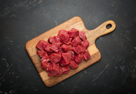 Diced cut raw beef cubes wooden cutting board red meat cooking protein top view