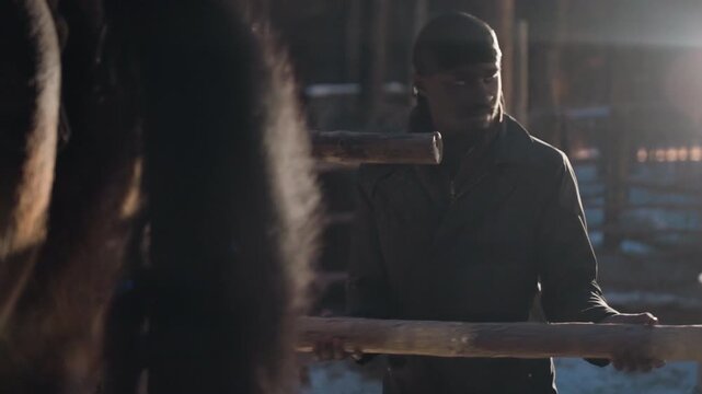 calm keeper beside horse under winter sky, serene deer keeper in icy farmyard with protecting stance, tranquil caretaker watches over horse against frosty barnyard backdrop with gentle touch