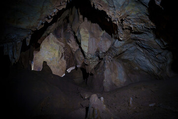 Dark limestone cave chamber with stalactites and rock formations