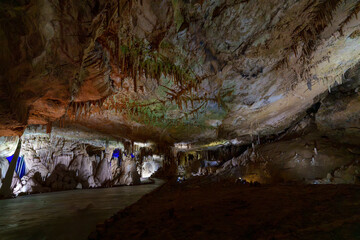 Illuminated show cave chamber with stalactites and textured limestone ceiling