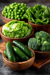 Fresh green vegetables, including lettuce, broccoli, cucumbers, and peas, in wooden bowls on a rustic table, ideal for healthy eating and organic lifestyle themes.