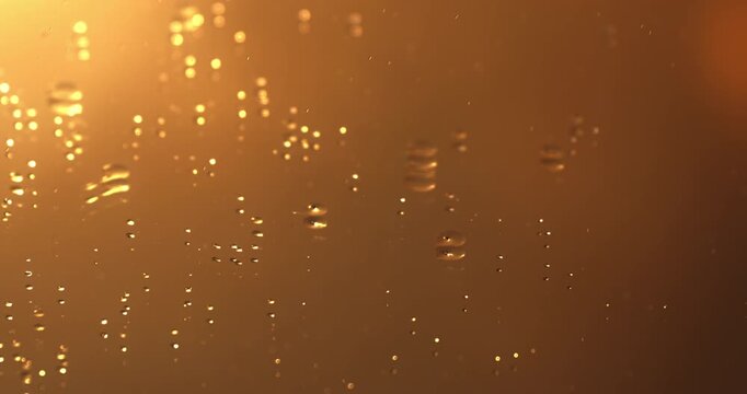Golden Droplets Falling In Slow Motion Against Warm Liquid Background Creating Soft Ripples And Elegant Fluid Patterns at 1000 fps.